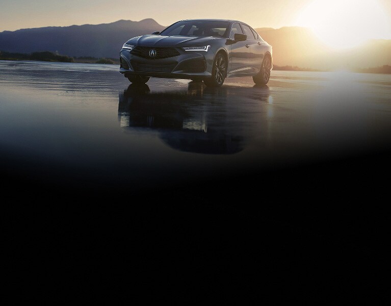2026 Acura TLX with Technology Package in Liquid Carbon Metallic, front three-quarter view at sunset with mountains (Premium Sport Sedan).