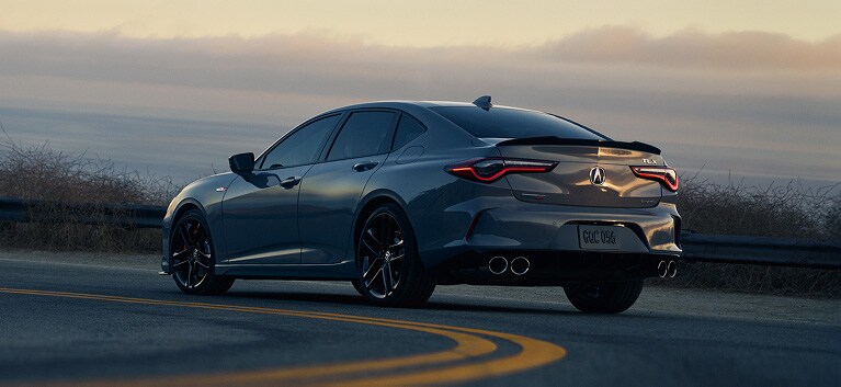 2026 Acura TLX with Technology Package in Liquid Carbon Metallic, rear view with a sunset in the background (Premium Sport Sedan).