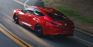 2026 Acura Integra A-Spec with Technology in Performance Red Pearl driving up road.
