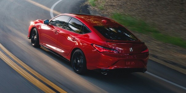 2026 Acura Integra A-Spec with Technology in Performance Red Pearl driving up road.